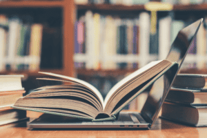 An open book sitting on top of an open laptop.