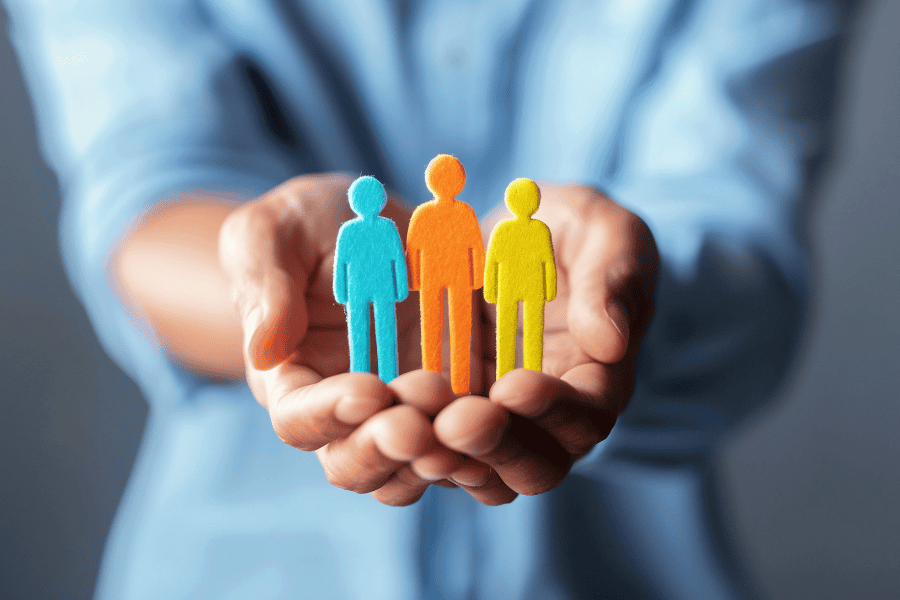 View of a person's hand holding blue, orange, and yellow fabric people.