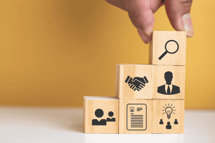 stacked building blocks with icons of people, ideas, handshake, and search icon