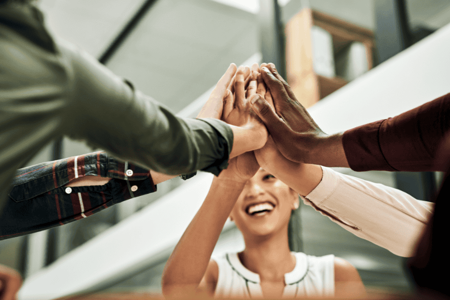 A group of business colleagues exchanging high fives to celebrate teamwork and achievements in the workplace.