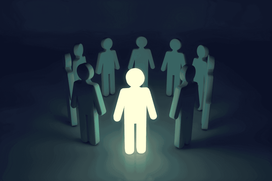 Full shot of a group of stylized figures, with one figure highlighted with a bright, luminous white light.