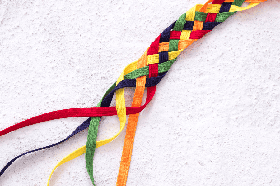 A vibrant rainbow-colored braided ribbon elegantly laid out on a white surface.