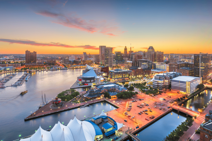 A picturesque view of Baltimore's skyline at sunset, with the serene Baltimore Harbor in the foreground.