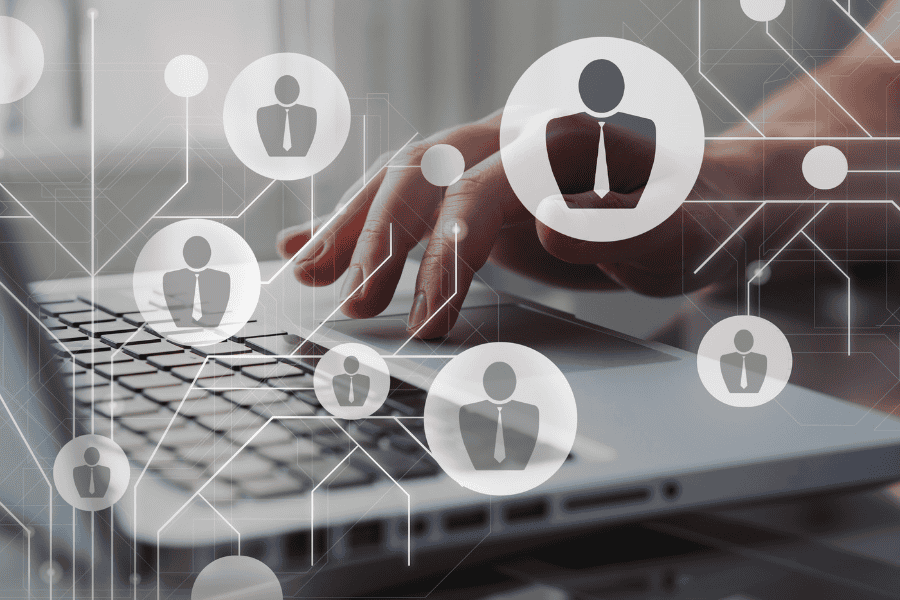 Close up of hands working at a laptop with graphic design overlay of web of icons of professionals.