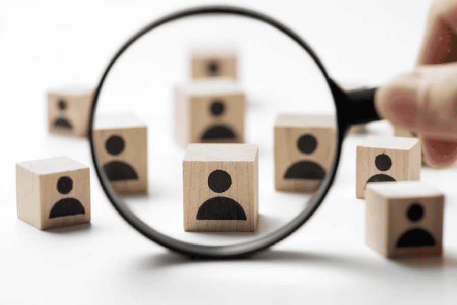 A magnifying class is held up to several wooden blocks with an outline of a person.
