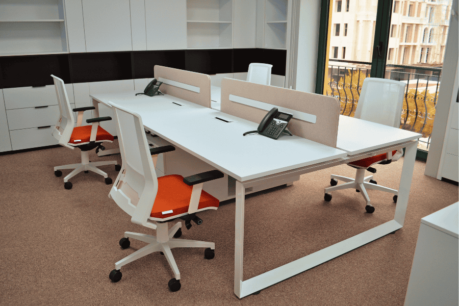 An office setup showcasing empty desks and chairs, promoting a functional work atmosphere.