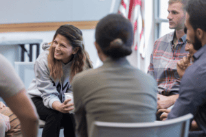 People sitting in circle engaged in conversation with focus on girl smiling