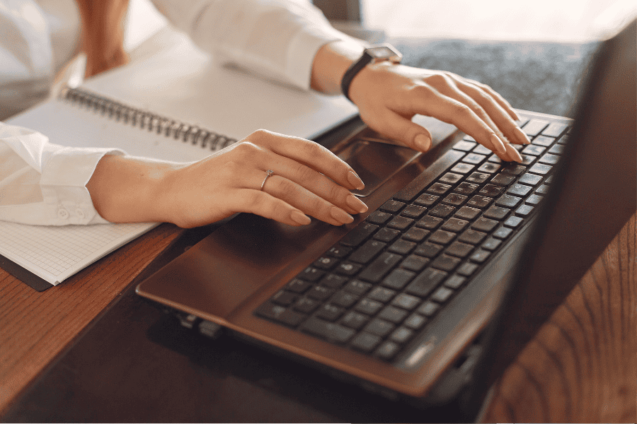 View of woman's hands typing on keyboard