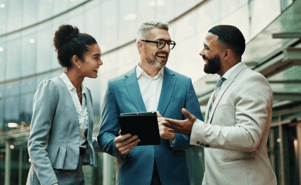 Three coworkers standing and talking in a huddle.