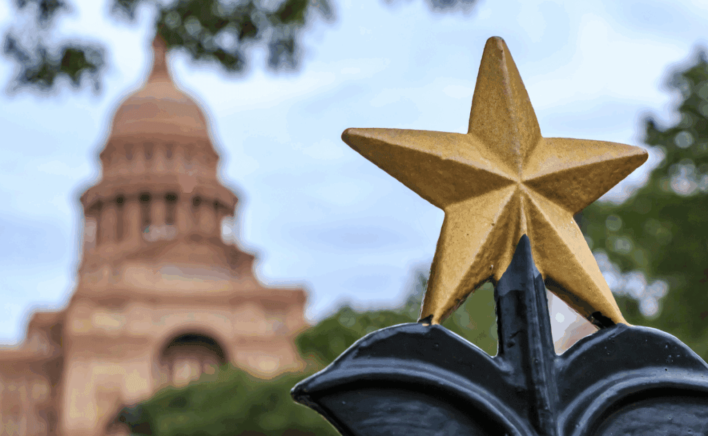 Star in forefront with the Texas Capitol building in the background.