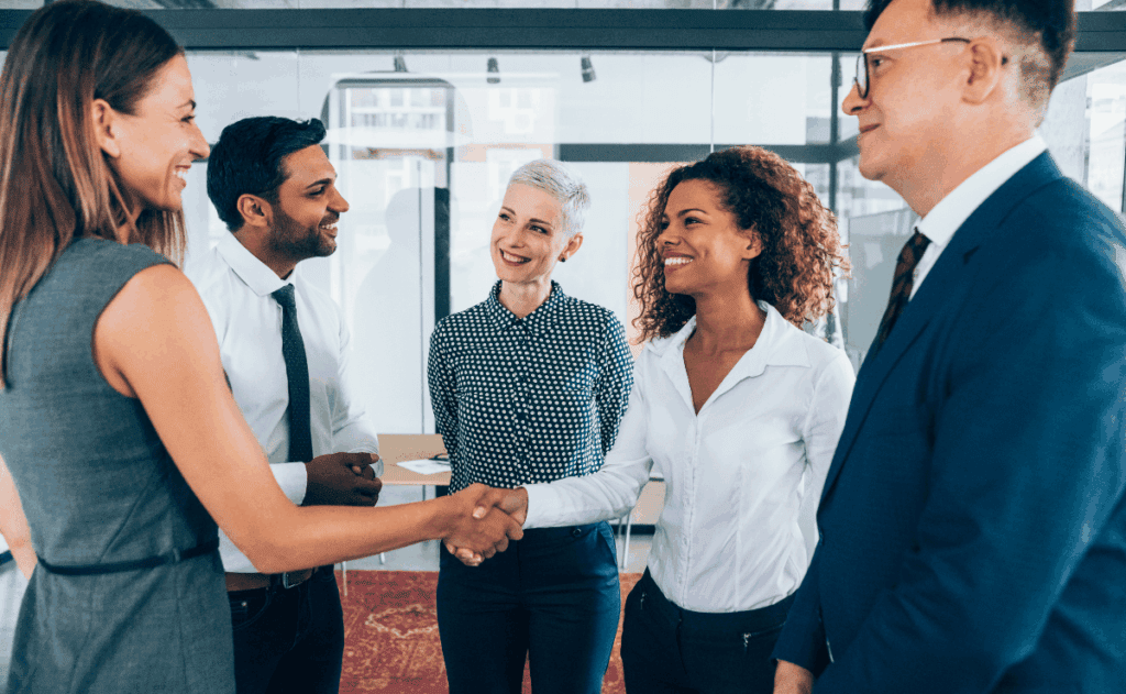 Two business people engaged in a handshake inside an office, representing collaboration and mutual agreement.