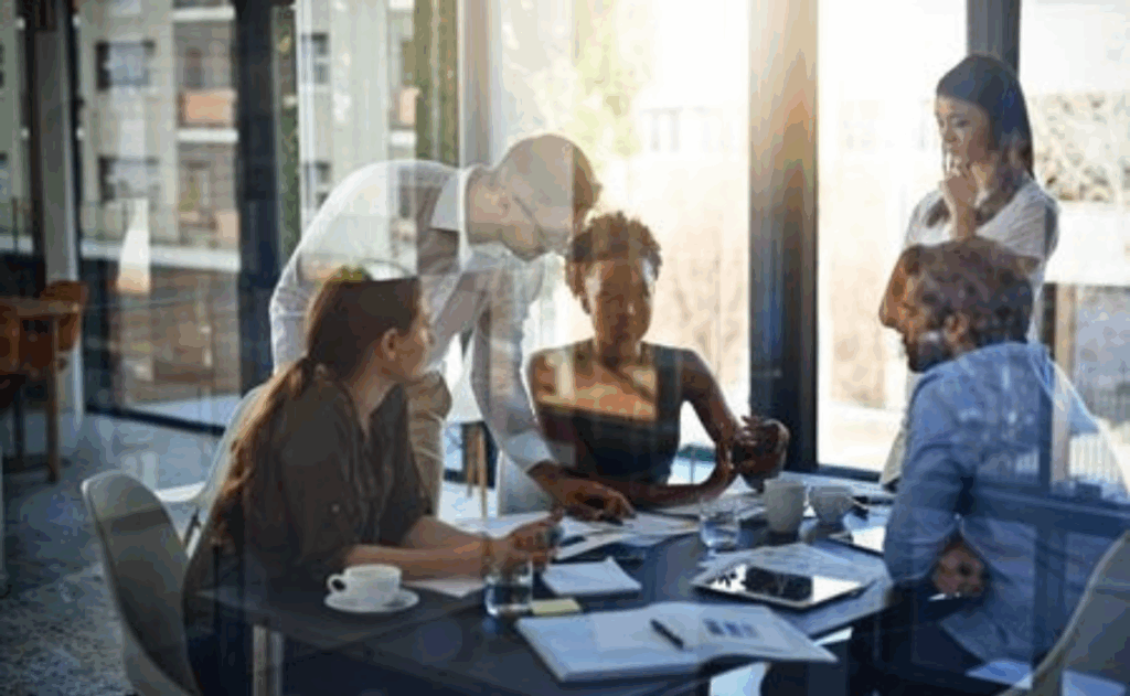 Group of professionals collaborating in a meeting as seen behind a glass plane.