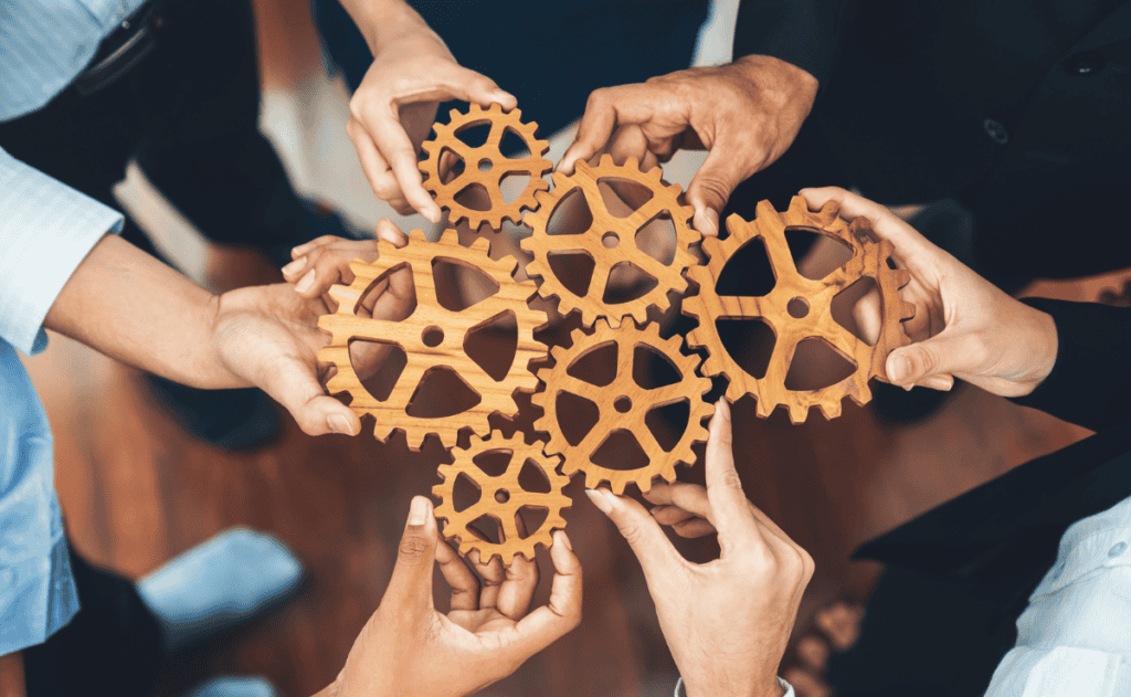 Concept image of office workers holding cog wheels as unity and teamwork.