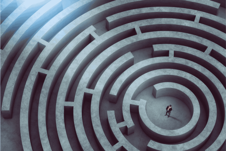 A person stands in the center of a circular maze, looking up as a light shines down from above.