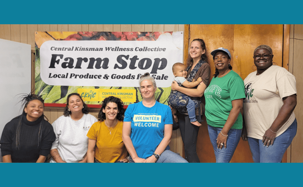 Group of volunteers posing indoors in front of a “Farm Stop” sign.